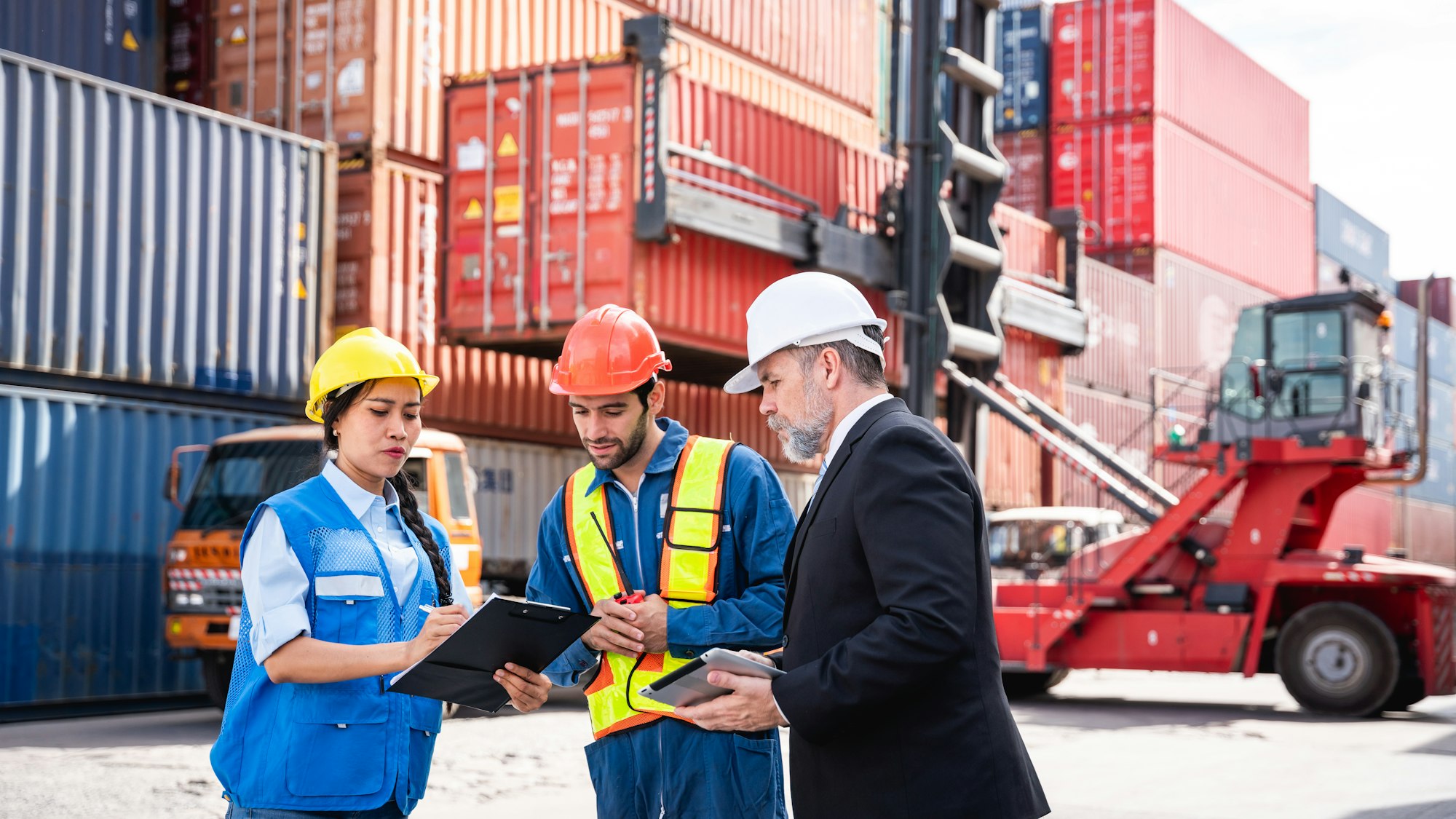Businessman, Engineer or foreman talking and checking inventory or task details at container yard.